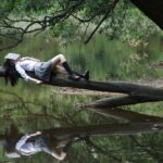 Girl reading on tree trunk in nature