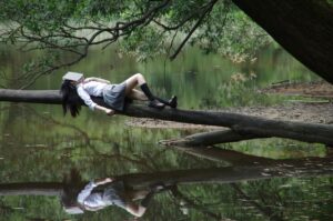 Girl reading on tree trunk in nature