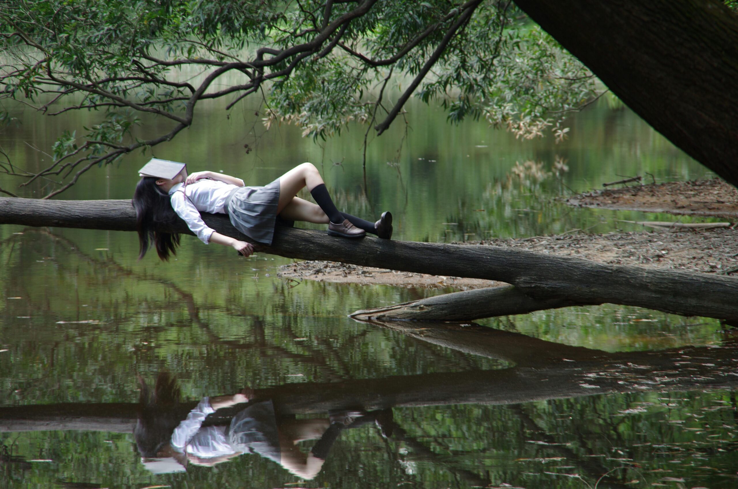 Girl reading on tree trunk in nature