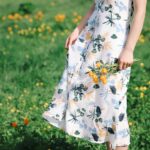 A woman in a sundress, holding a bouquet in a floral meadow.