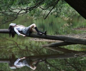 Girl reading on tree trunk in nature